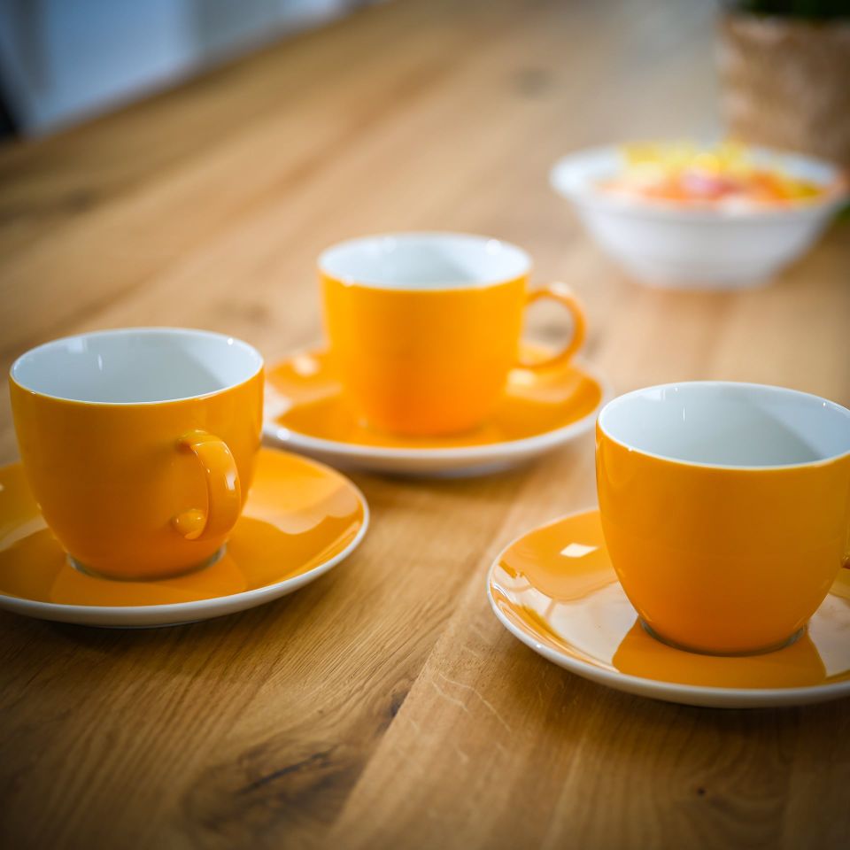 Orangene Tassen auf einem Holztisch