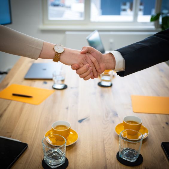 Handschlag zwischen einer Frau und einem Mann über einem Tisch